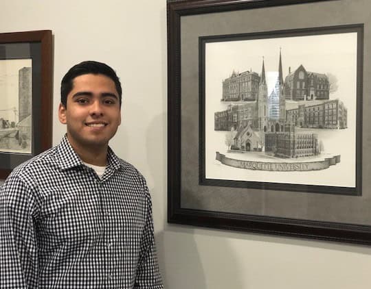 Man smiling beside framed university architectural drawing