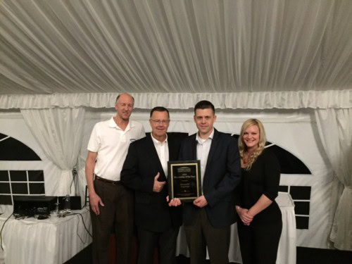 Four people presenting an award plaque at an event