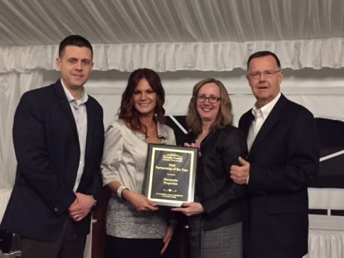 Four people smiling with an award at an event